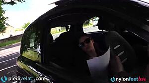 Brunette in black pantyhose displaying her feet from the car